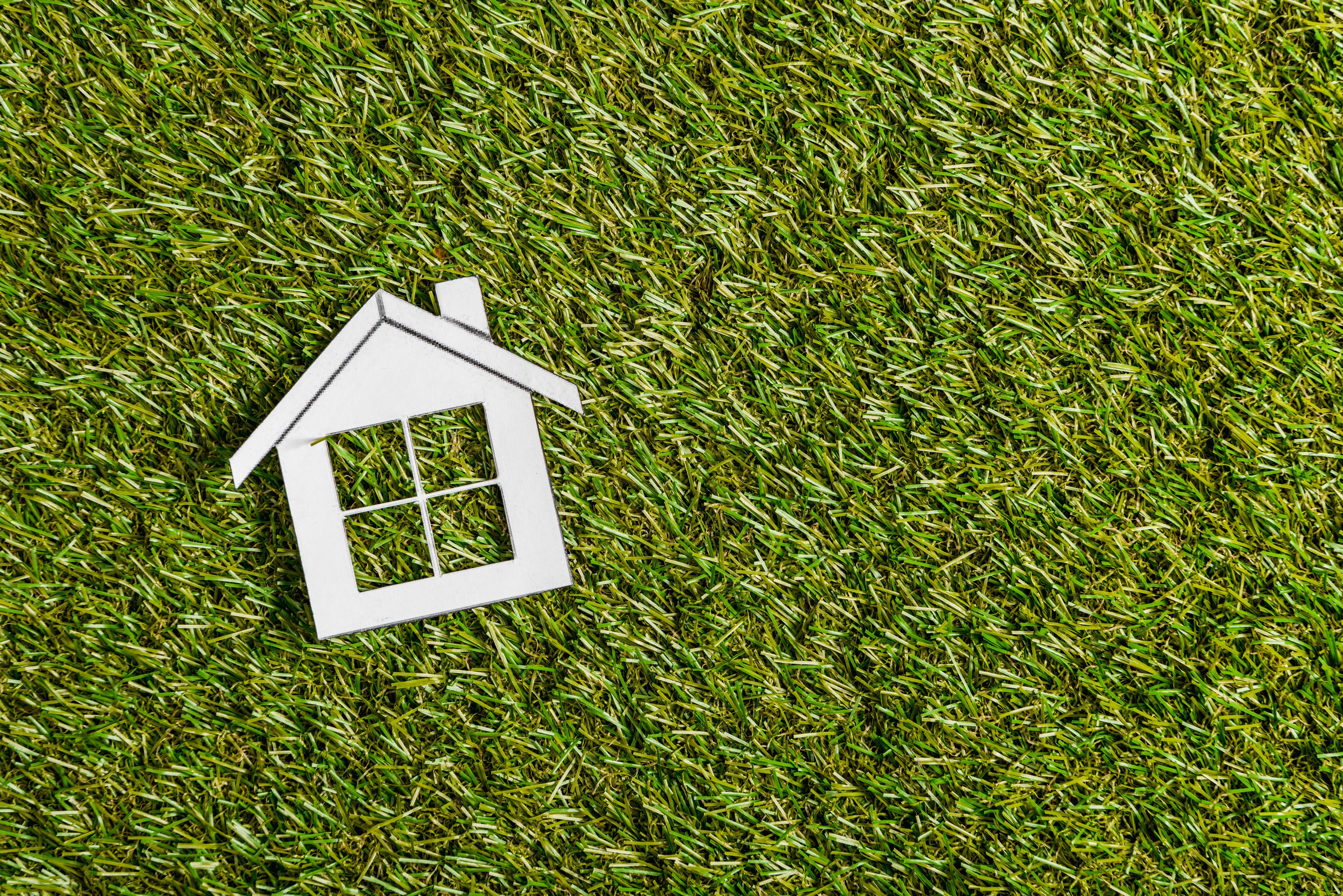 vista superior de una casa de papel blanco sobre hierba verde, eficiencia energética