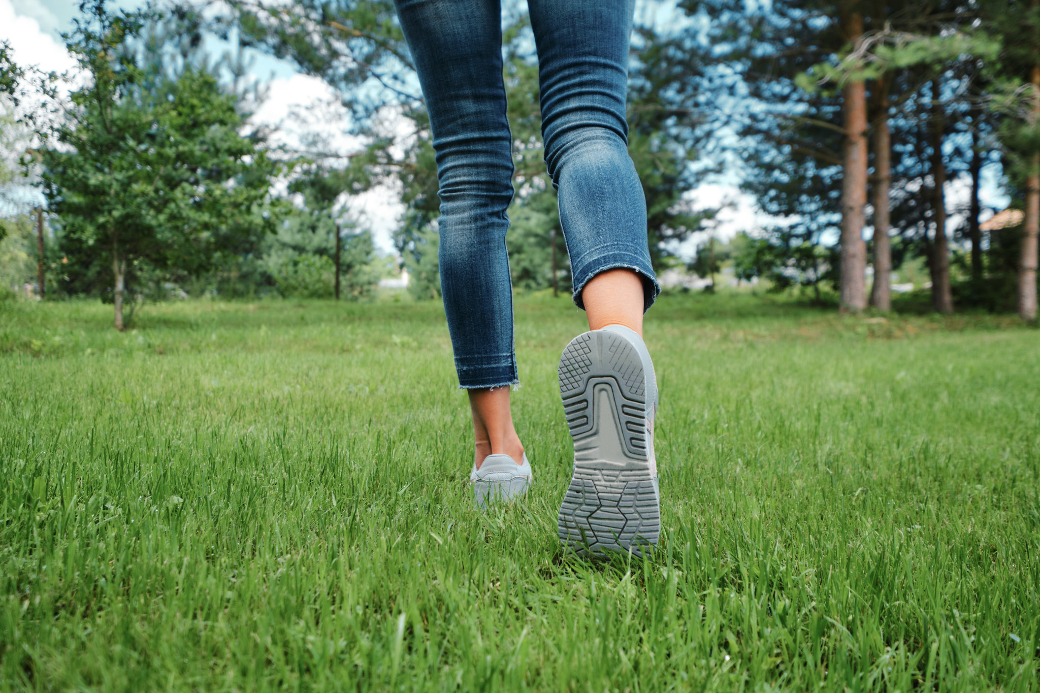 Vista en ángulo bajo de la suela de un zapato de una mujer caucásica caminando por la hierba.