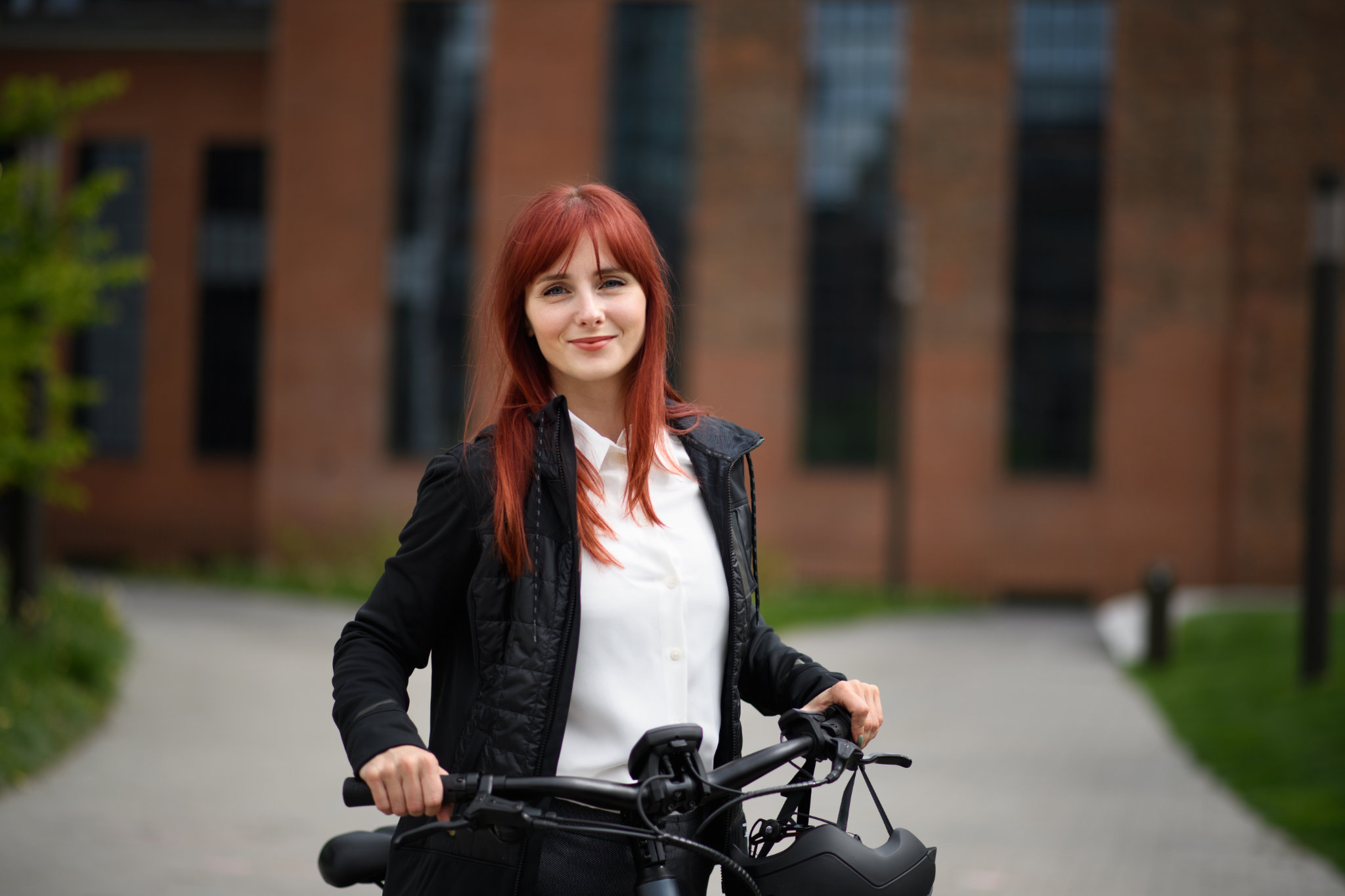 Un retrato de una mujer de negocios que viaja al trabajo en bicicleta mirando la cámara, un concepto de estilo de vida sostenible.