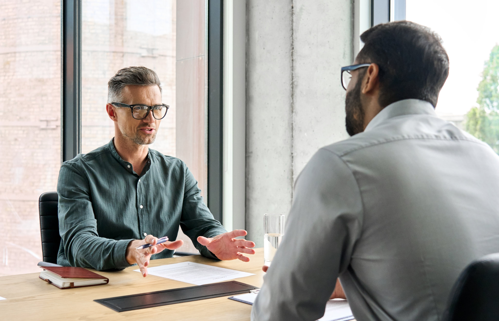 Dos socios ejecutivos de negocios diversos que negocian en una reunión, un asesor energético que consulta a un cliente sentados a la mesa en la oficina.