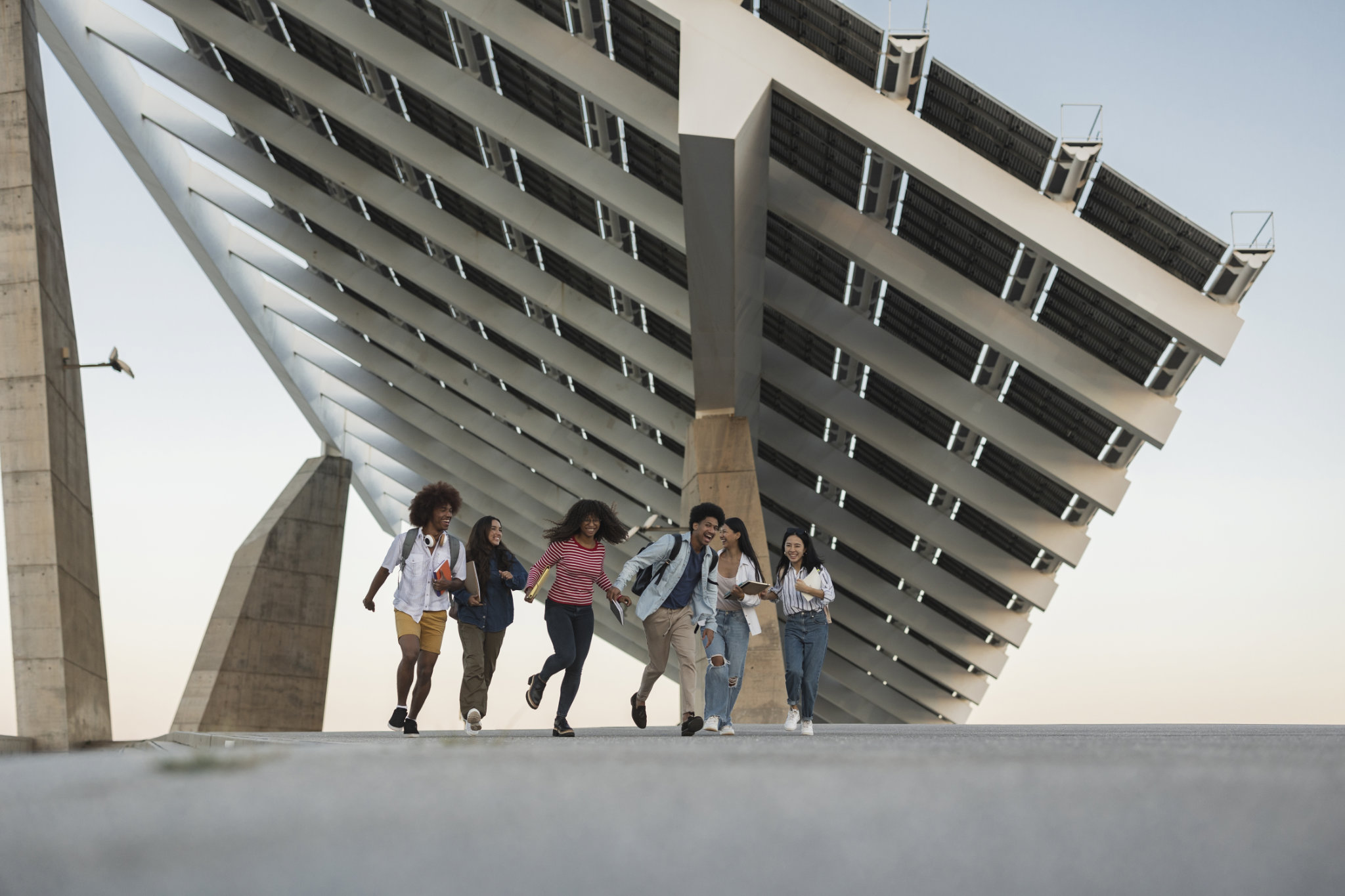 Grupo de estudiantes corriendo debajo de una estructura moderna de paneles solares