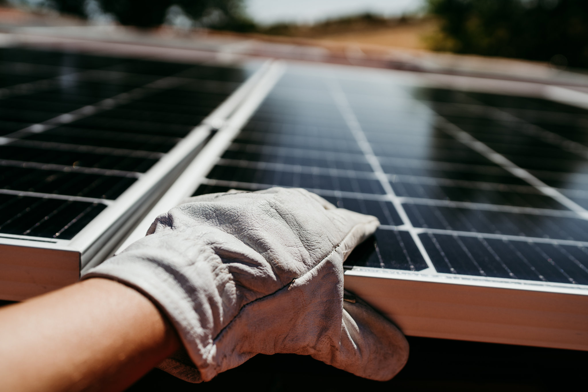 primer plano de la mano de un técnico maduro que toca paneles solares en el techo de la casa para energía de autoconsumo. Energías renovables y concepto de energía verde.
