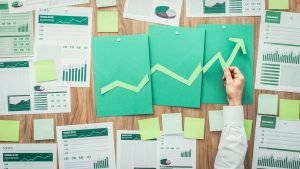 Empresario que compone un gráfico financiero exitoso con una flecha que sube, está usando recortes de papel verde, negocios ecológicos y concepto de éxito financiero